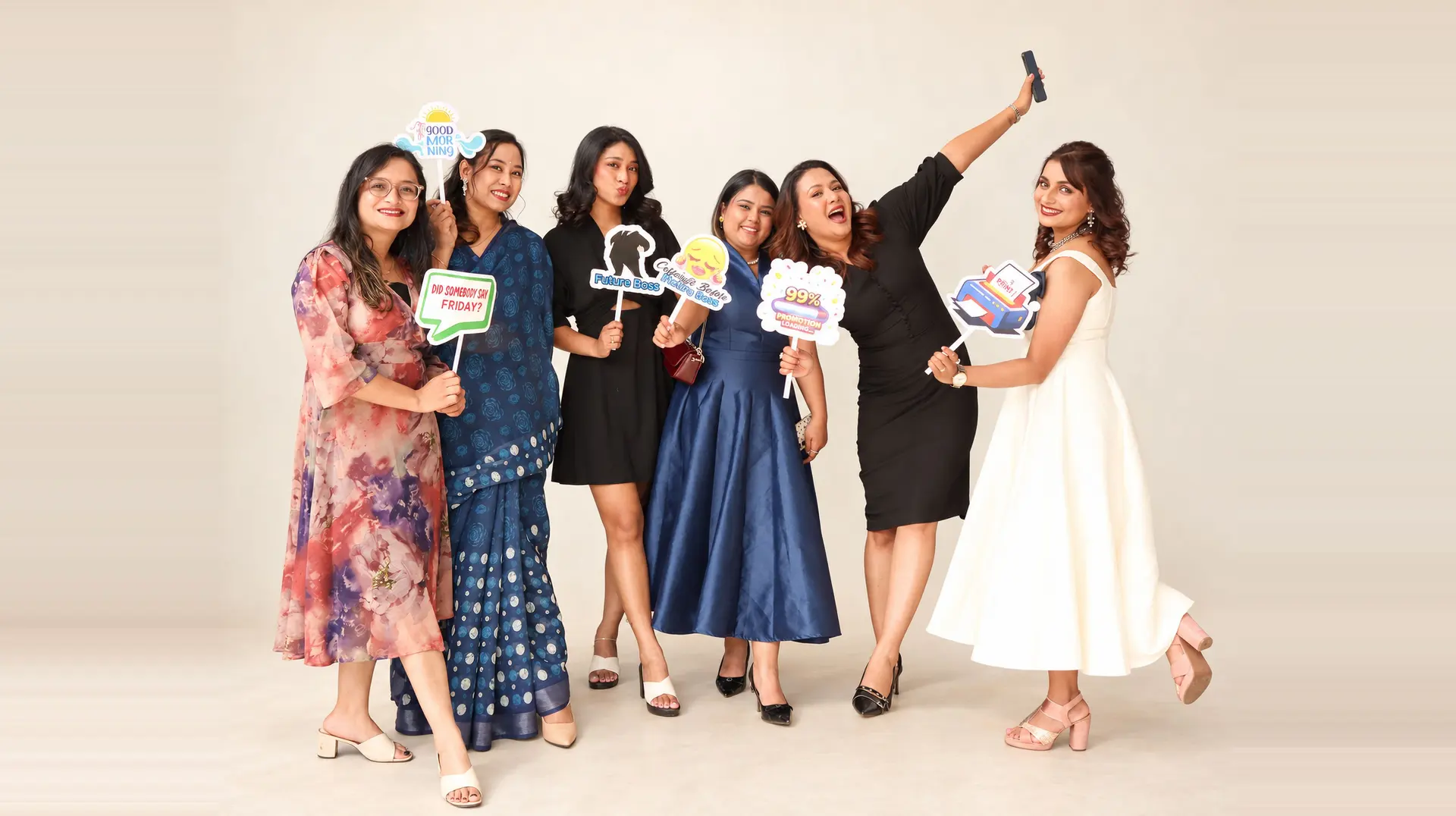 Six Manaram colleagues laughing together with photo-booth props